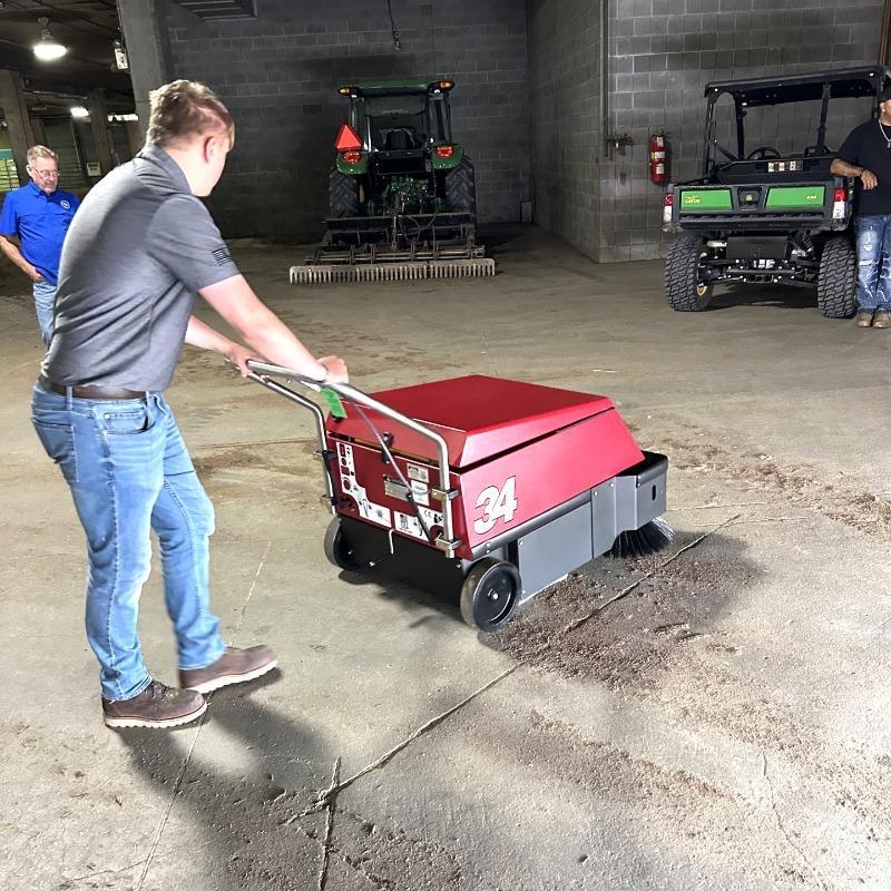 FactoryCat Walk Behind Floor Sweepers 34 backstage concrete - https://assets.factorycat.com/demoImages/2025/april/34-Walk Behind Floor Sweepers-backstage-concrete-Kansas City -USA-461.jpg - 800 - 800 - 461 A FactoryCat 34 walk behind battery floor sweeper cleaning the concrete floor at the rodeo in Kansas City, MO