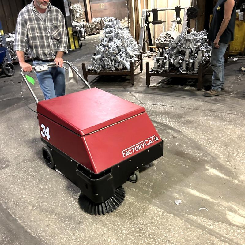 FactoryCat Walk Behind Floor Sweepers 34 maintenance halls concrete - https://assets.factorycat.com/demoImages/2025/april/34-Walk Behind Floor Sweepers-maintenance halls-concrete-St. Louis-USA-407.jpg - 800 - 800 - 407 A FactoryCat 34 battery floor sweeper cleaning the concrete maintenance shop floor of a foundry in St. Louis, MO