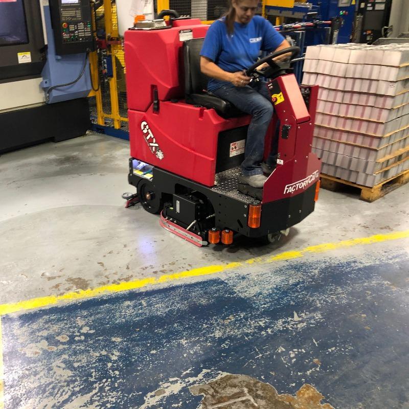 FactoryCat Ride On Floor Scrubbers GTX production floor concrete - https://assets.factorycat.com/demoImages/2025/april/GTX-Ride On Floor Scrubbers-production floor-concrete-Knoxville-USA-818.jpg - 800 - 800 - 818 A FactoryCat GTX Ride On Floor Scrubber is cleaning the concrete floor in a Knoxville, Tennessee fabrication shop