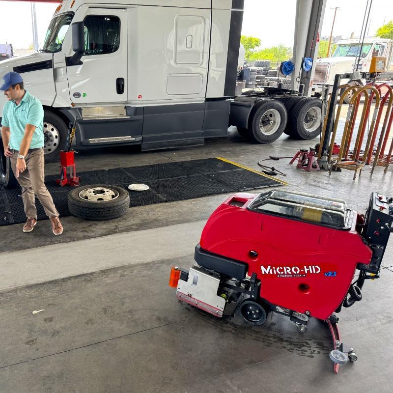 FactoryCat Walk Behind Floor Scrubbers Micro-HD service bay concrete - https://assets.factorycat.com/demoImages/2025/april/Micro-HD-Walk Behind Floor Scrubbers-service bay-concrete-Pheonix-USA-432.jpg - 800 - 800 - 432 A FactoryCat Micro-HD battery floor scrubber cleaning the concrete floor of a tire shop service bay in Phoenix, AZ