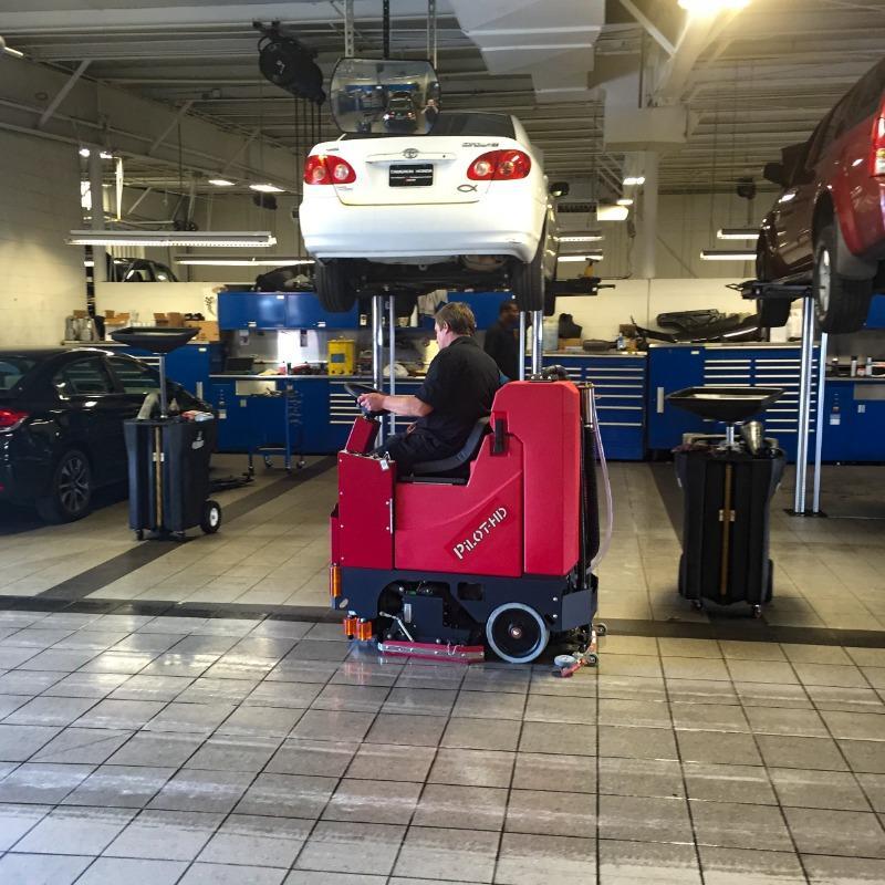 FactoryCat Ride On Floor Scrubbers Pilot service department tile floors - https://assets.factorycat.com/demoImages/2025/april/Pilot-Ride On Floor Scrubbers-service department-tile floors-Macon-USA-842.jpg - 800 - 800 - 842 A FactoryCat Pilot Ride On Floor Scrubber cleans the oily and greasy tile floor of a Macon, Georgia car dealership