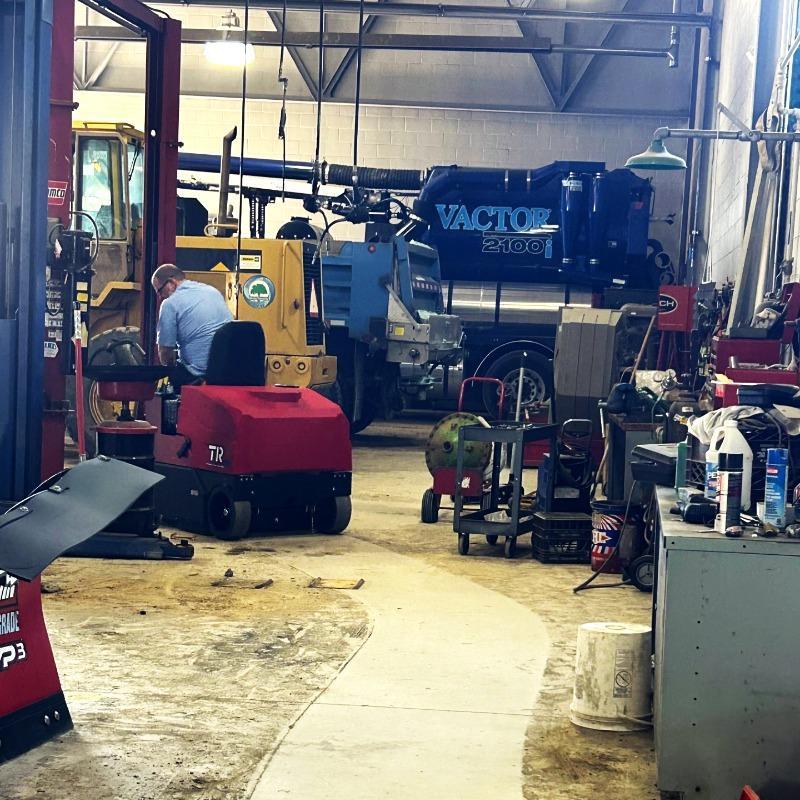 FactoryCat Ride On Floor Sweepers TR production floor concrete - https://assets.factorycat.com/demoImages/2025/april/TR-Ride On Floor Sweepers-production floor-concrete-St. Louis-USA-483.jpg - 800 - 800 - 483 A FactoryCat TR rider floor sweeper cleaning the concrete floor in a maintenance shop of a municipality in Richmond, VA