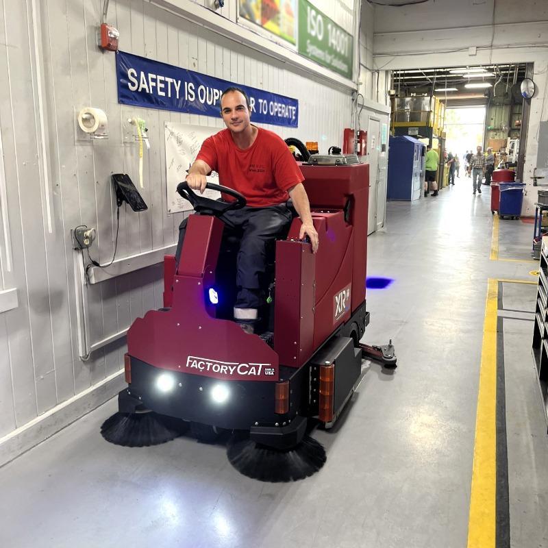 FactoryCat Ride On Floor Scrubbers XR production areas epoxy - https://assets.factorycat.com/demoImages/2025/april/XR-Ride On Floor Scrubbers-production areas-epoxy-Norcross-USA-448.jpg - 800 - 800 - 448 A FactoryCat XR battery rider floor scrubber cleaning epoxy in the aisles of a manufacturing facility in Norcross, GA