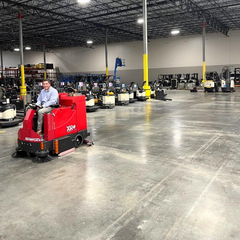 FactoryCat Ride On Floor Scrubbers XR warehouse concrete - https://assets.factorycat.com/demoImages/2025/april/XR-Ride On Floor Scrubbers-warehouse-concrete-Austr-USA-622.jpg - 800 - 800 - 622 FactorytCat XR ride on auto scrubber cleaning the concrete warehouse floor in Austin, Texas