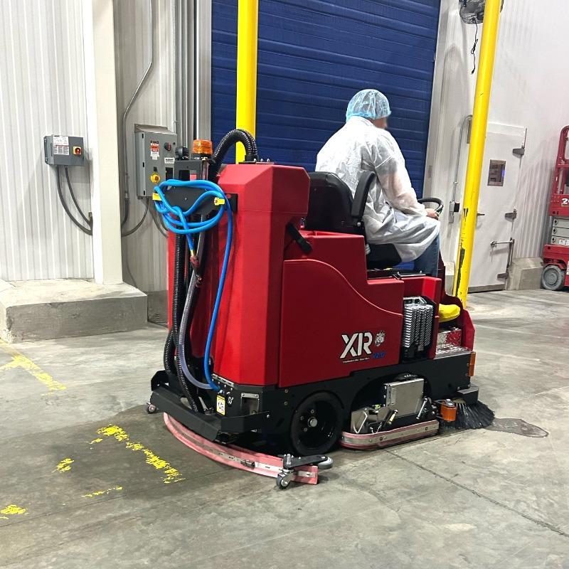 FactoryCat Ride On Floor Scrubbers XR warehouse concrete - https://assets.factorycat.com/demoImages/2025/april/XR-Ride On Floor Scrubbers-warehouse-concrete-Waco-USA-413.jpg - 800 - 800 - 413 A FactoryCat XR battery floor scrubber cleaning the concrete floor of a food manufacturer's warehouse in Waco, TX